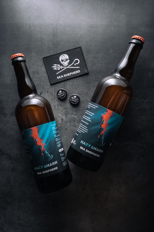 Deux bouteilles de bière Sea Shepherd Hazy Shark IPA, patch avec logo et deux pins Sea Shepherd Don't drink and dive